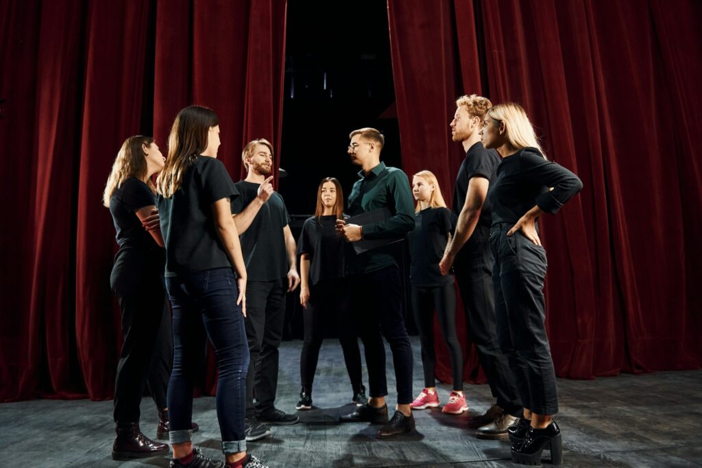 Group of actors in dark colored clothes on rehearsal in the theater